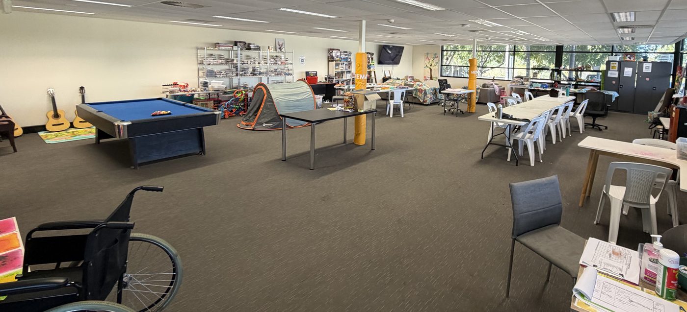 The first floor at Boowan Court: a pool table and guitars at one end, a play tent, shelves of games and craft supplies, and long tables set out across the open space