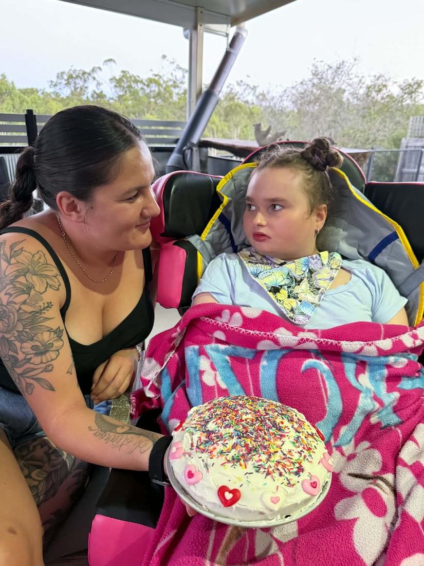 A Lionheart support worker holding out a decorated cake to Shontae