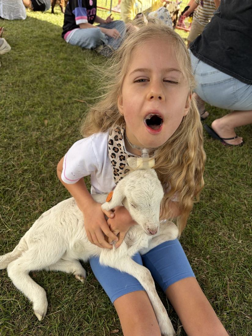 Florence sitting on the grass holding a lamb, laughing