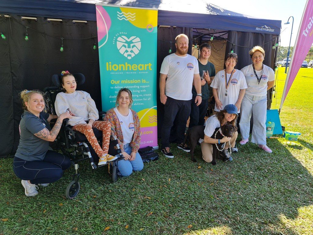 Lionheart staff and participants together under a marquee at Rainbow on the Reef, beside a Lionheart banner