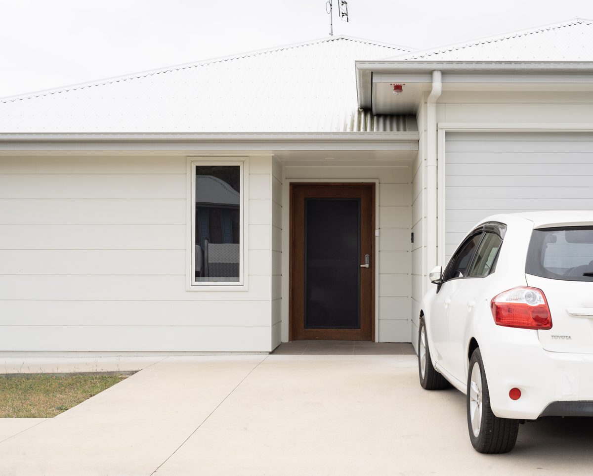 One of the Lionheart SIL homes from the street: a single-storey house with a front door, a garage and a car in the driveway